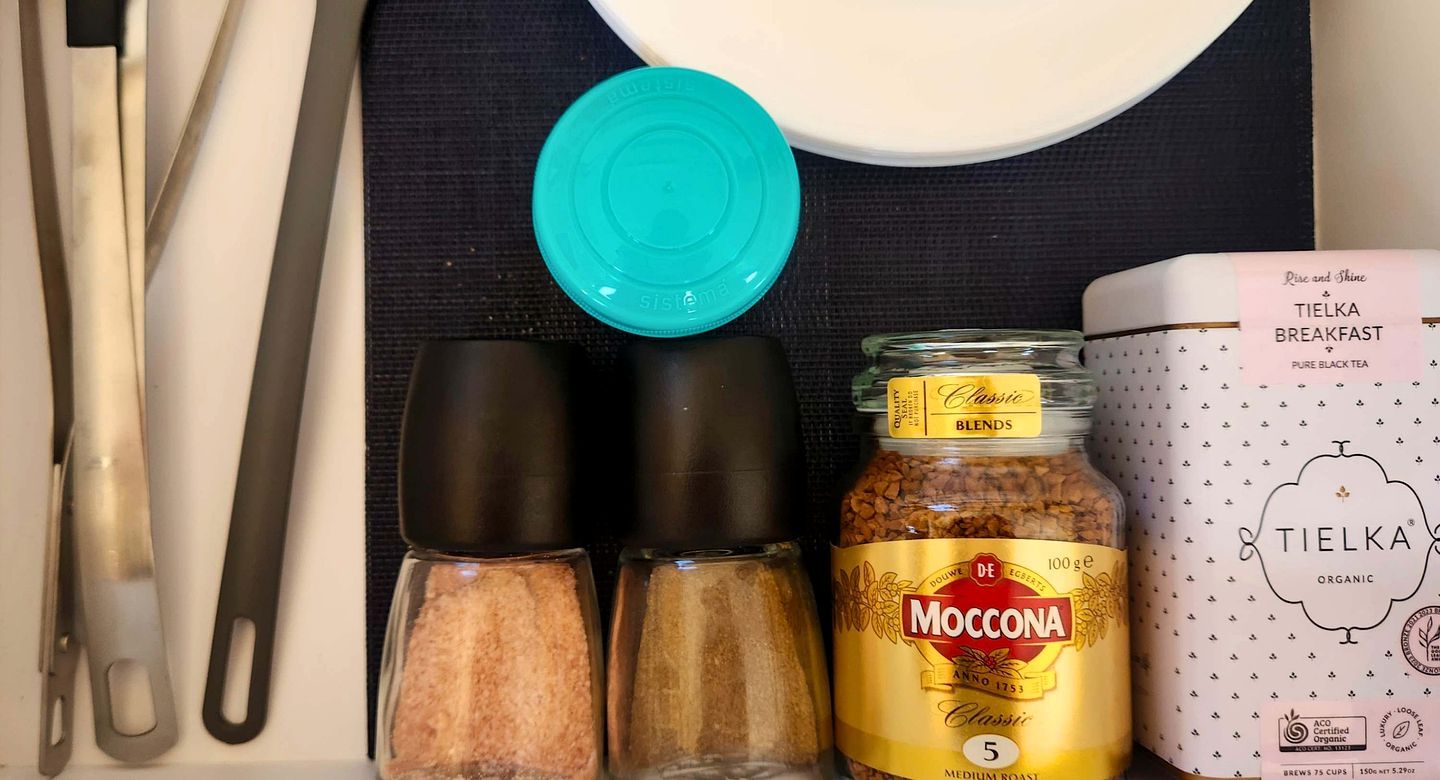 Een keukentrap met een pot Moccona Classic Medium Roast, een doos Tielka Breakfast Pure Black Tea, en twee zoutvaatjes.