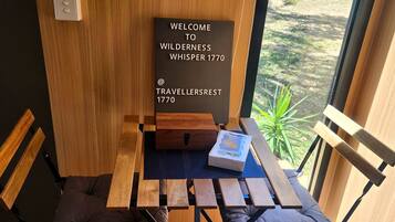 A wooden bench with a small table, a welcome sign, and a box on the table.