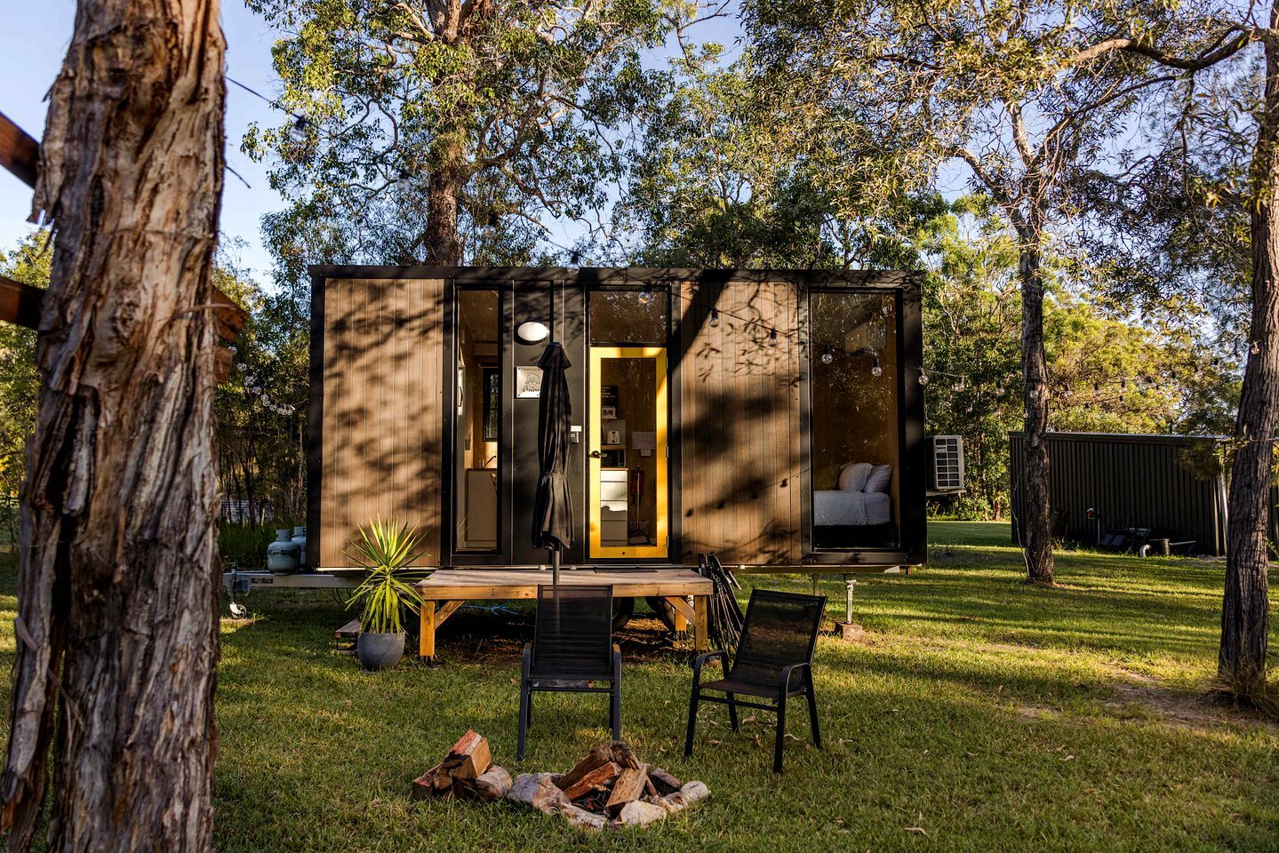 A wooden cabin with a glass door, a bench, and chairs outside.