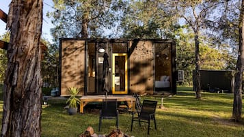 A wooden cabin with a glass door, a bench, and chairs outside.