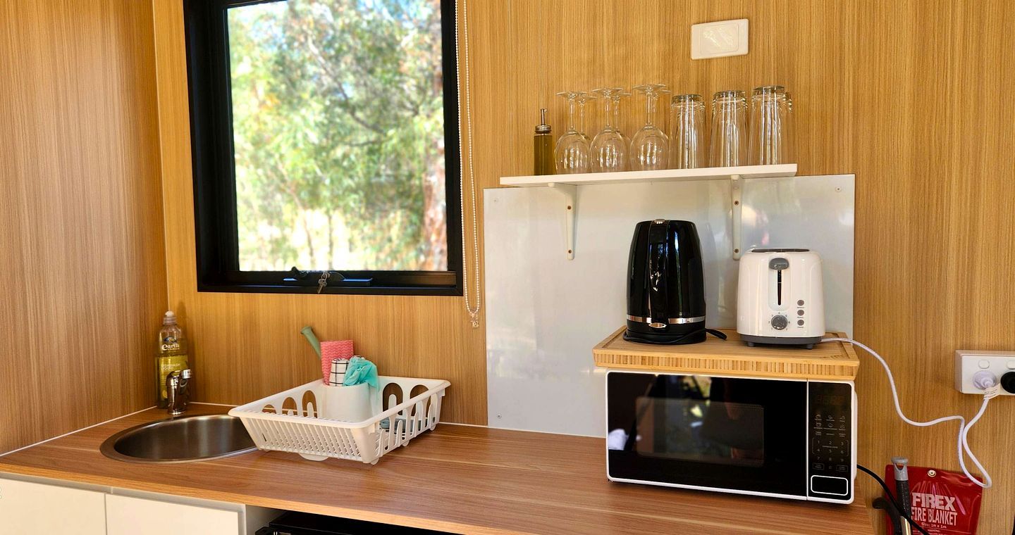 Eine kleine Küche mit Mikrowelle, Toaster, Kaffeemaschine und einer Korb voller Gegenstände.