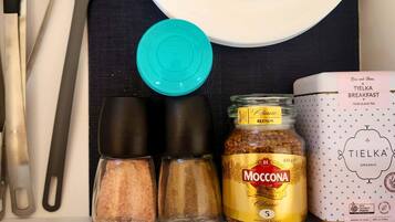 Een keukentrap met een pot Moccona Classic Medium Roast, een doos Tielka Breakfast Pure Black Tea, en twee zoutvaatjes.
