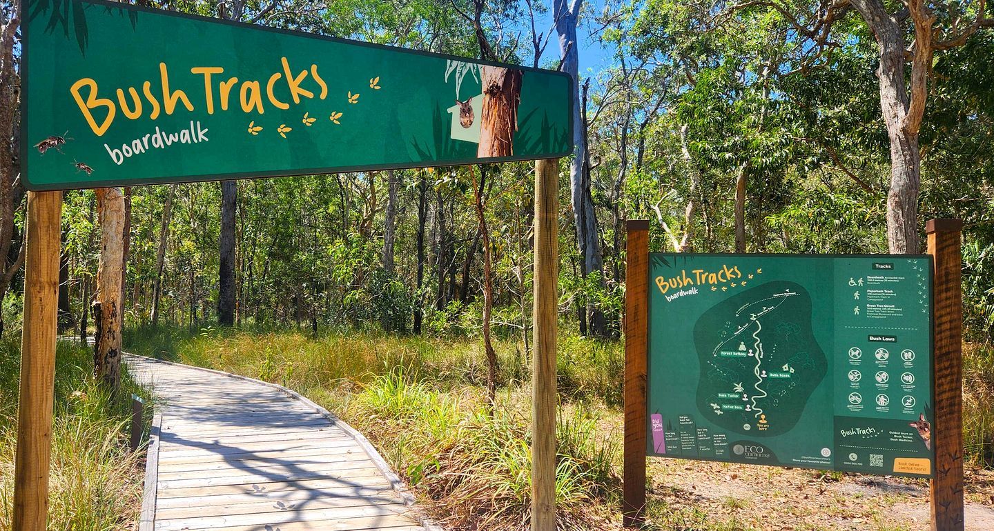 Ein Promenadeweg mit der Beschriftung 'Bush Tracks', einer Karte und einem Informationsschild.