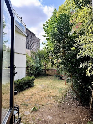 Ein Garten mit vielfältigen Pflanzen und einem Gebäude mit schrägem Dach.
