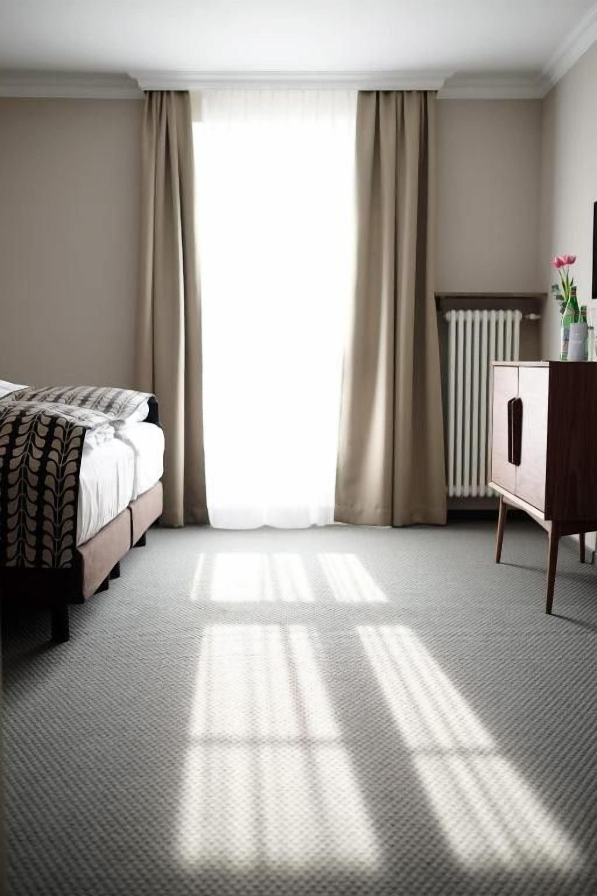 A hotel room with a bed, a radiator, and a cabinet.