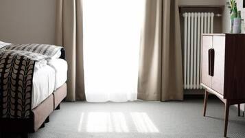 A hotel room with a bed, a radiator, and a cabinet.