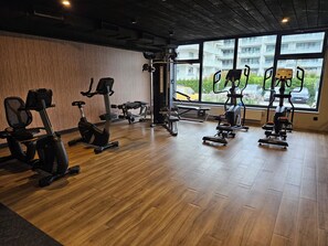 A gym with various exercise equipment, large windows, and a view of the outside. - A fully furnished apartment just 5 minutes from a wide, sandy beach. (Kołobrzeg)