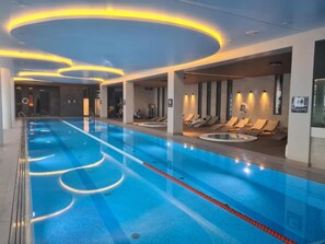 A swimming pool with a long, narrow shape, surrounded by lounge chairs and sunbeds, and a ceiling with circular light fixtures. - A fully furnished apartment just 5 minutes from a wide, sandy beach. (Kołobrzeg)