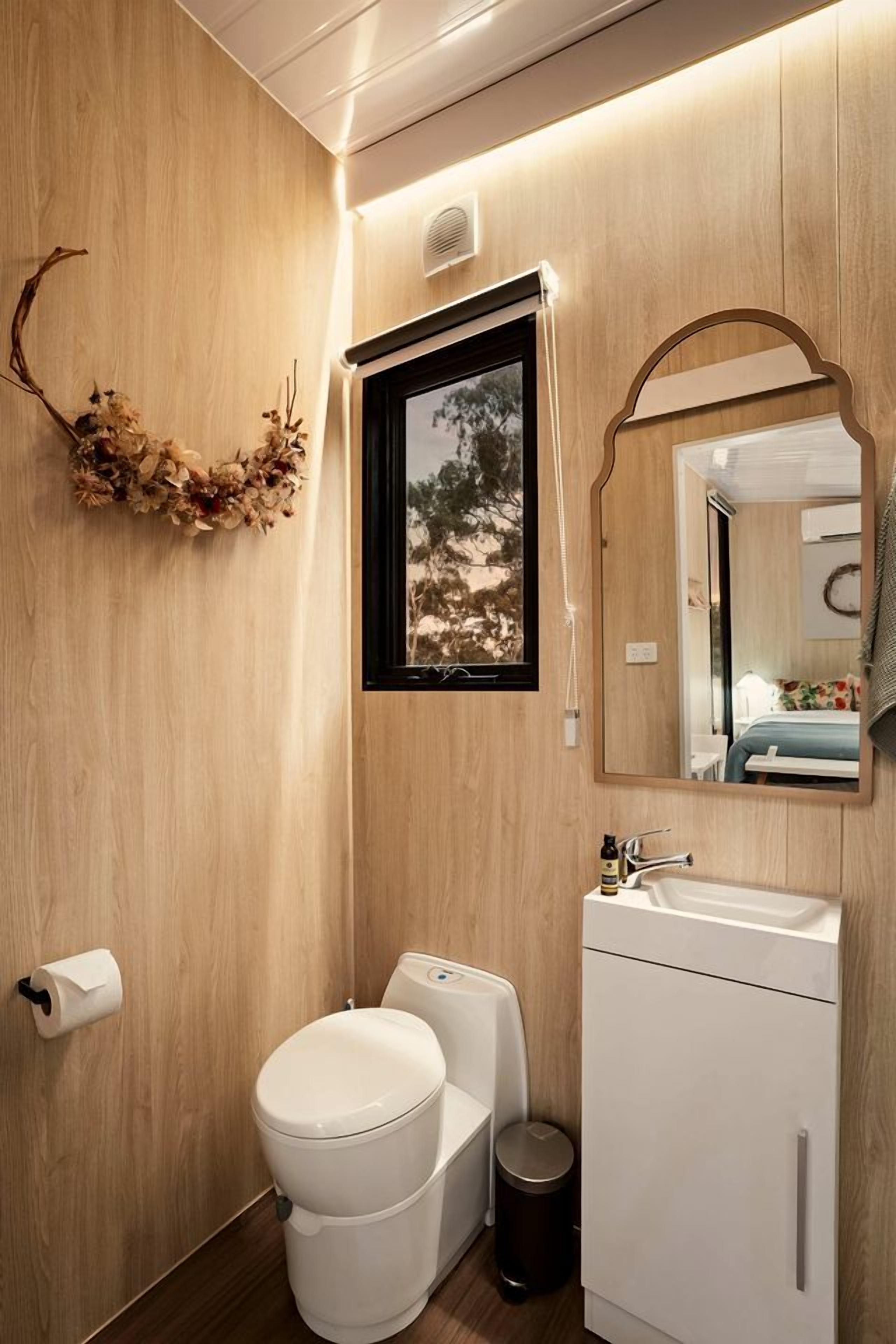 Un baño moderno con pared de madera, inodoro, lavabo y espejo.