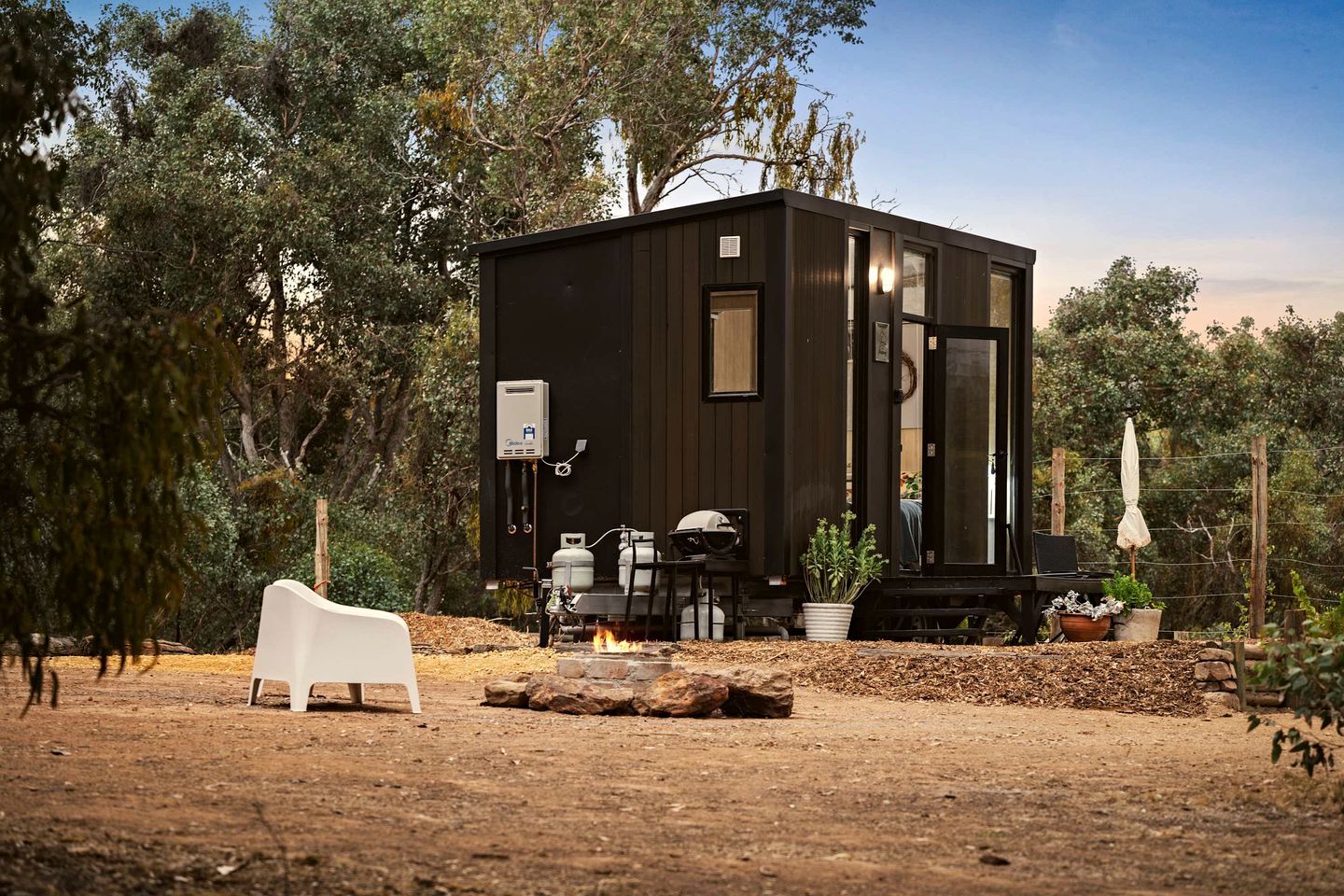 A compact cabin with a small porch, a fire pit, and outdoor seating.