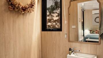 A modern bathroom with a wooden wall, a toilet, a sink, and a mirror.