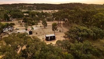 A rural landscape with a small cabin surrounded by trees and open fields.