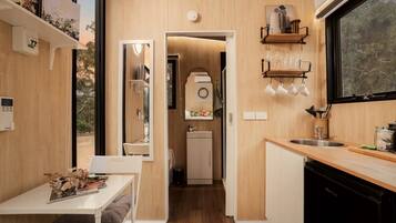 A compact kitchen with a sink, a small refrigerator, and a dining area with a table and chairs.