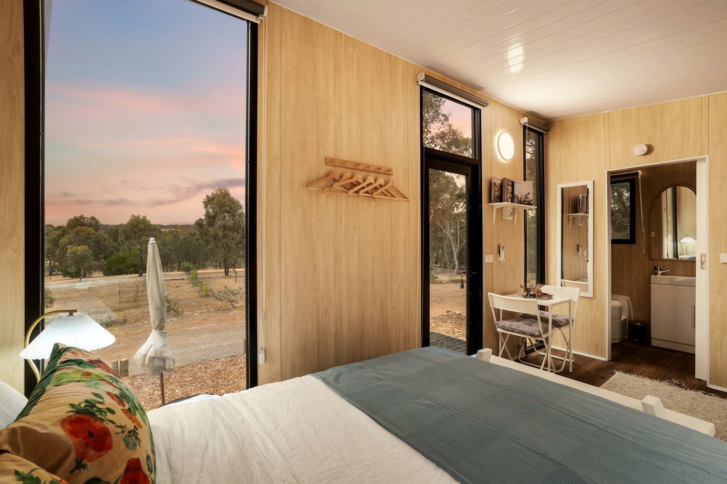 Un dormitorio con una ventana grande, una cama, un escritorio y un baño.