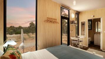 Un dormitorio con una ventana grande, una cama, un escritorio y un baño.