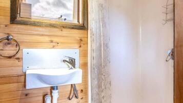 A wooden interior with a white sink, a shower, and a window with a view.