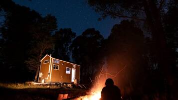 Eine Hütte mit kleiner Veranda, Feuerstelle und sternenklarer Nacht.