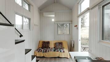 Ein kleines Zimmer mit Bett, Tisch, Fenster und integrierter Klimaanlage.