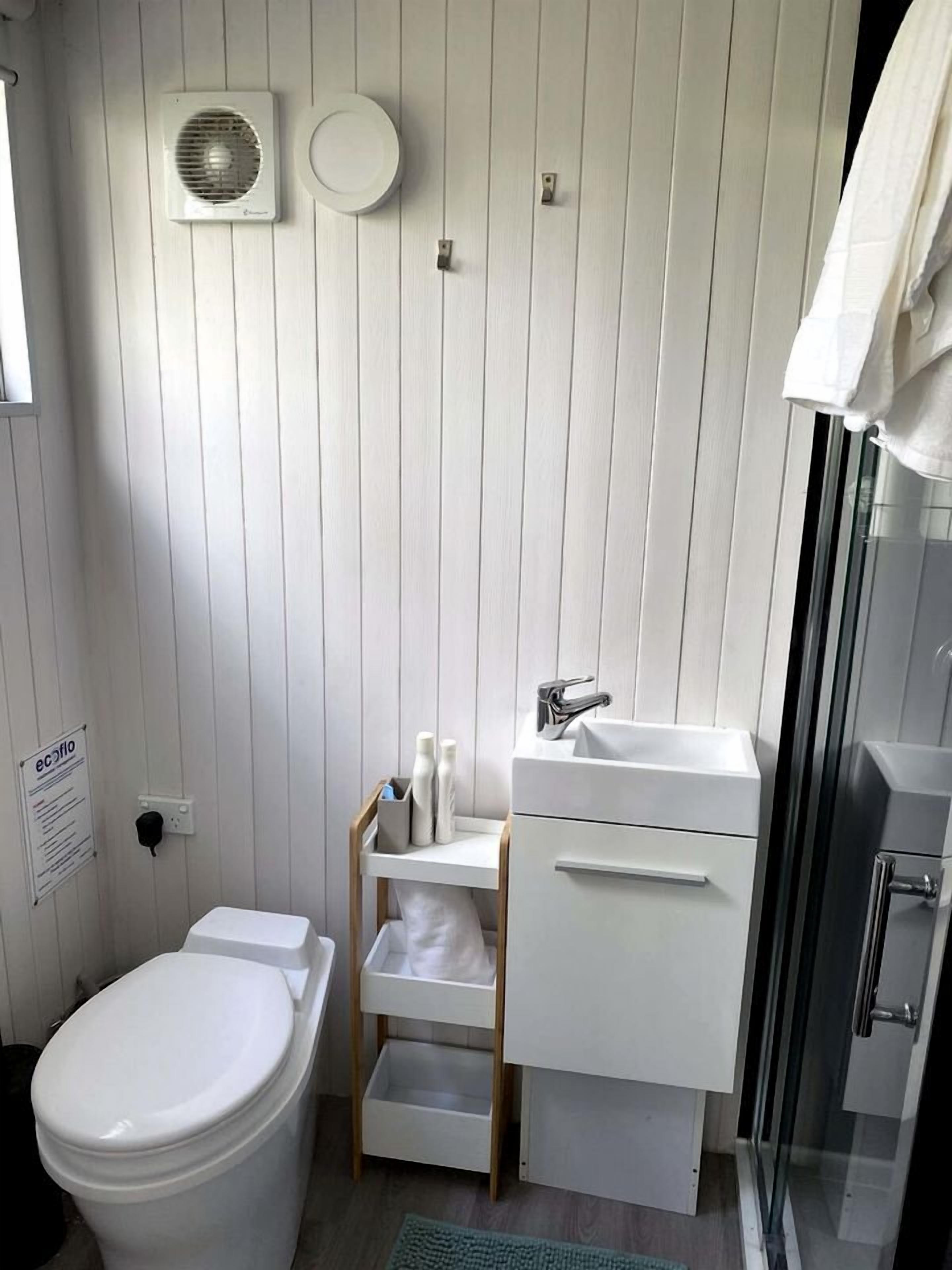 Ein Badezimmer mit Toilette, Waschbecken, Dusche und Handtuchhalter.
