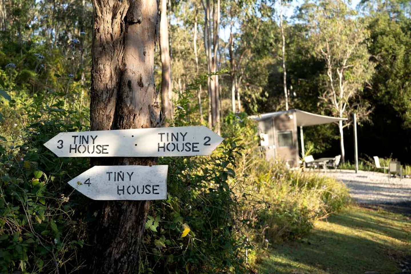 A directional signpost with arrows pointing to 'Tiny House 3', 'Tiny House 2', and 'Tiny House 4'.