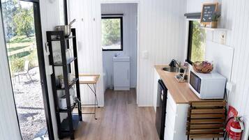 A compact kitchen with a wooden countertop, a microwave, and a small sink.