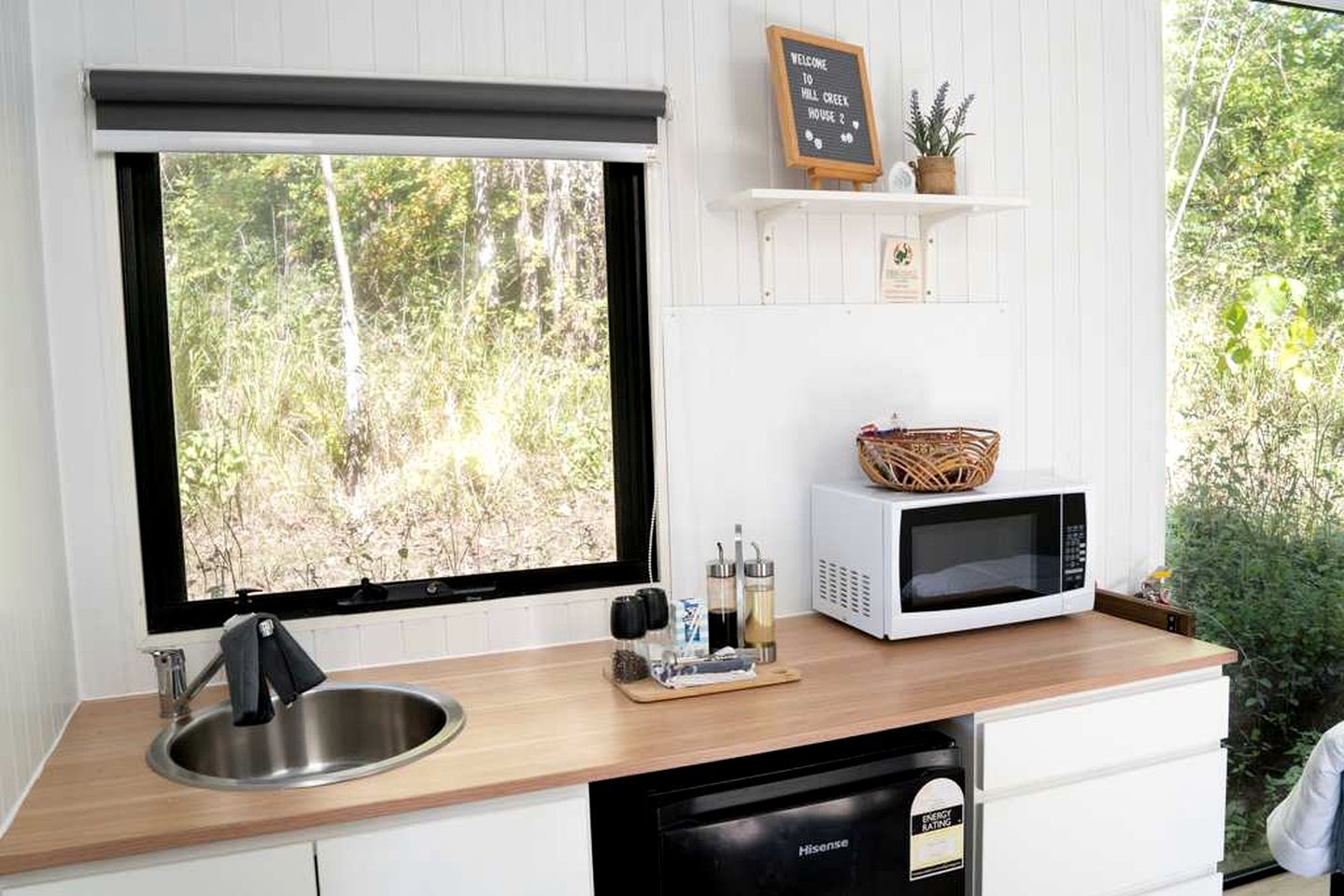 A kitchen with a large window, a microwave, a sink, and a dishwasher.