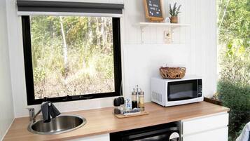 A kitchen with a large window, a microwave, a sink, and a dishwasher.