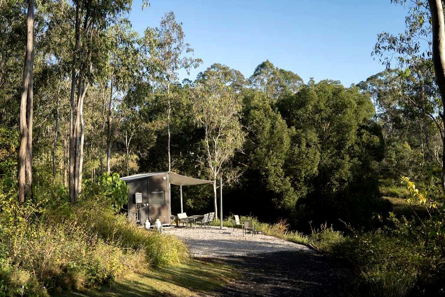 A small, single-story building with a covered patio area, surrounded by dense forest.