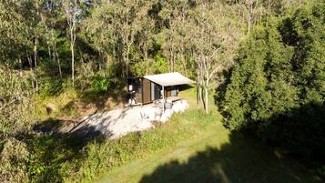 A small cabin with a metal roof and a single door, surrounded by dense forest.