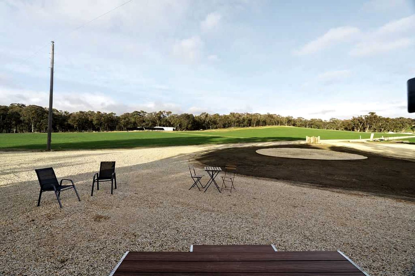 Un área de estar al aire libre con sillas y mesas, suelo de grava y vista a un campo de golf.