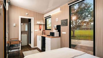Un dormitorio moderno con una cama grande, un escritorio con una computadora y vistas al exterior.