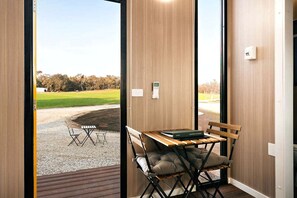 Una habitación con interior de madera, una mesa con sillas, un banco y vistas a un área verde exterior.