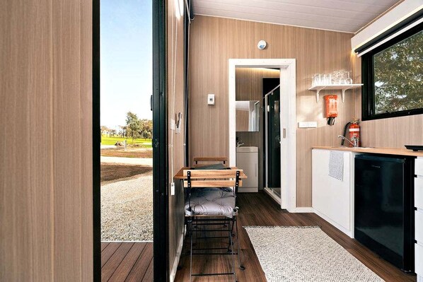 A compact kitchen with a built-in refrigerator, a small dining area with a bench, and a view of the outdoors.