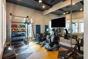 Un gimnasio con equipo de ejercicio, un televisor y un espejo.