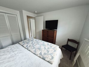 Ein Schlafzimmer mit einem Bett, einem Schminktisch, einem Fernseher und einem Sessel.