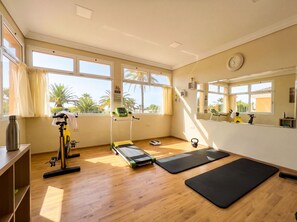 Une pièce équipée d’un tapis de course, de tapis de sol pour les exercices, d’une balance et d’un kettlebell.