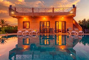 Une maison moderne dotée d’une piscine, d’un espace salon extérieur et d’un balcon.