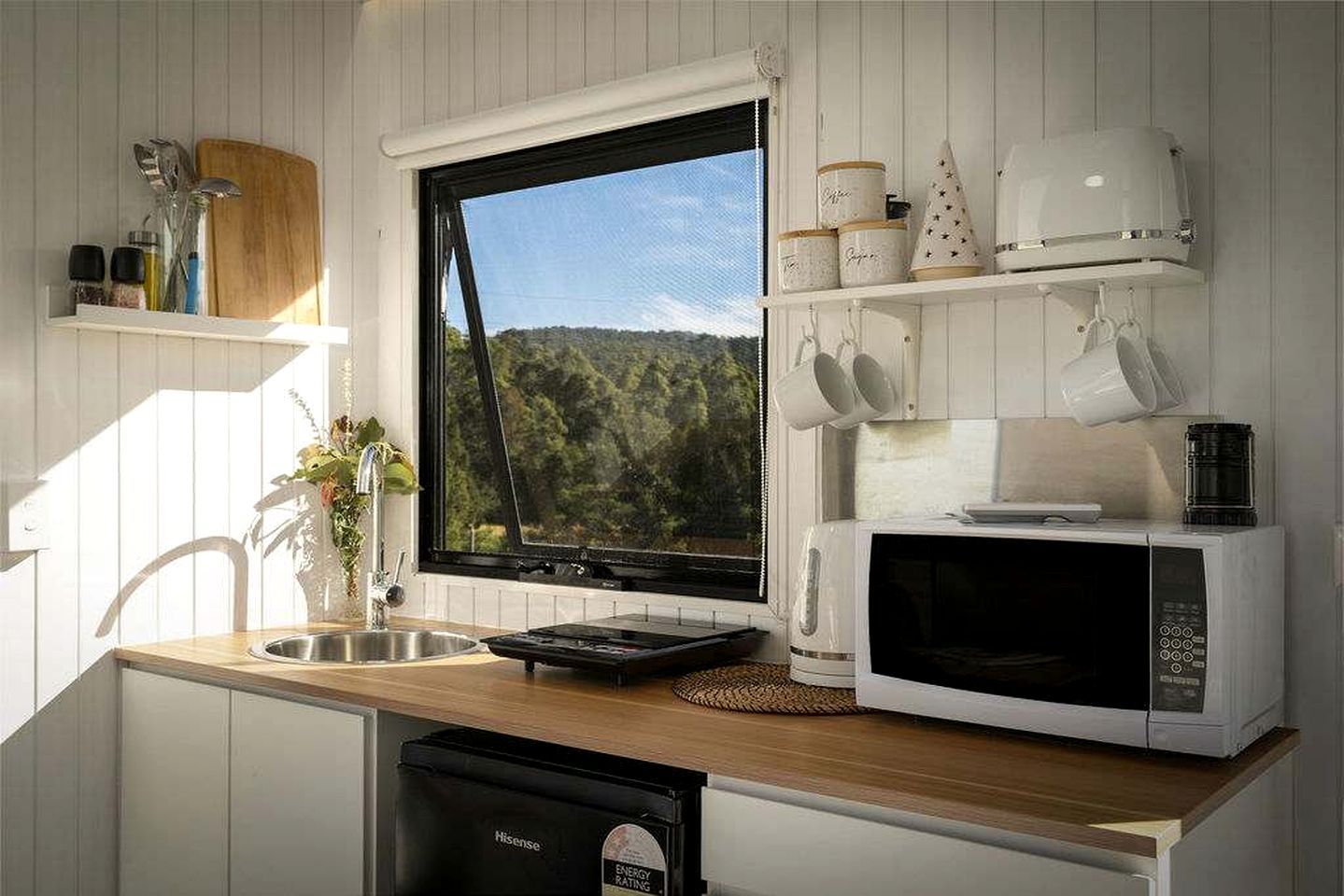 A kitchen with a window, a microwave, and a sink.