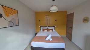 A bedroom with a bed, a hanging light fixture, a wall decoration, and a door. - Premium 5-bedroom villa · pool · air conditioning · Sud Sauvage (Saint-Philippe)