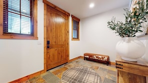 A wooden door with a window, a bench, a potted plant, and a tiled floor. - Mountain Modern, Quiet Location, Private Laundry & Complex Hot Tub (Mammoth Lakes)