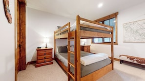A bunk bed with a wooden frame, a bedside table with a lamp, a dresser, and a map on the wall. - Mountain Modern, Quiet Location, Private Laundry & Complex Hot Tub (Mammoth Lakes)