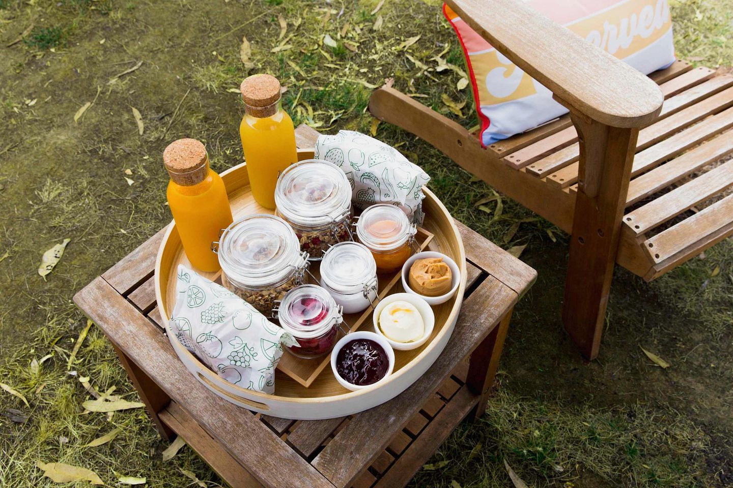 A wooden picnic table with a tray containing various food items and drinks.