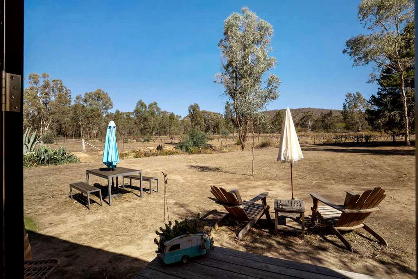 An outdoor seating area with tables and chairs, a small vehicle, and umbrellas.