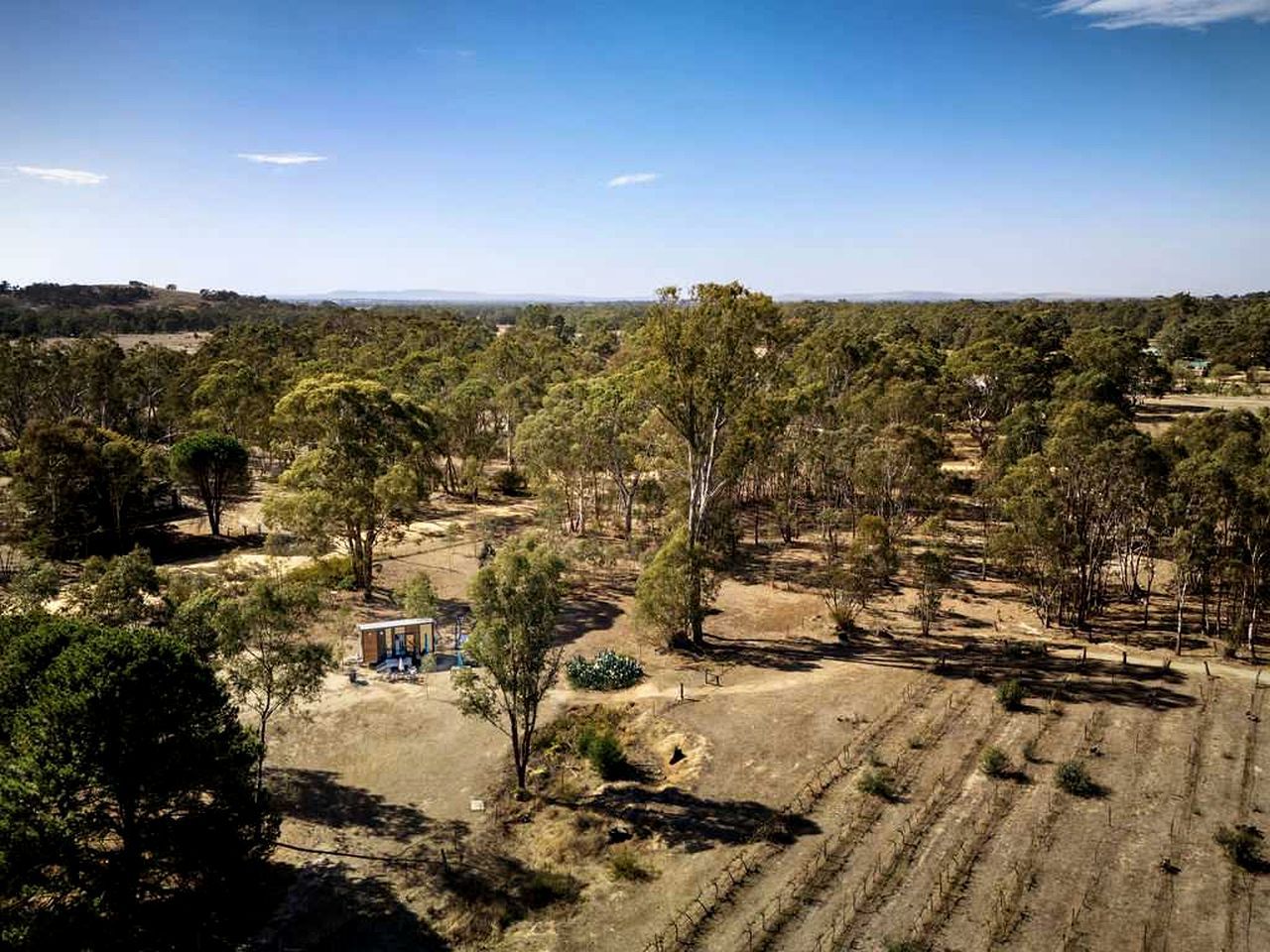 A rural landscape with a small building surrounded by trees and open fields.