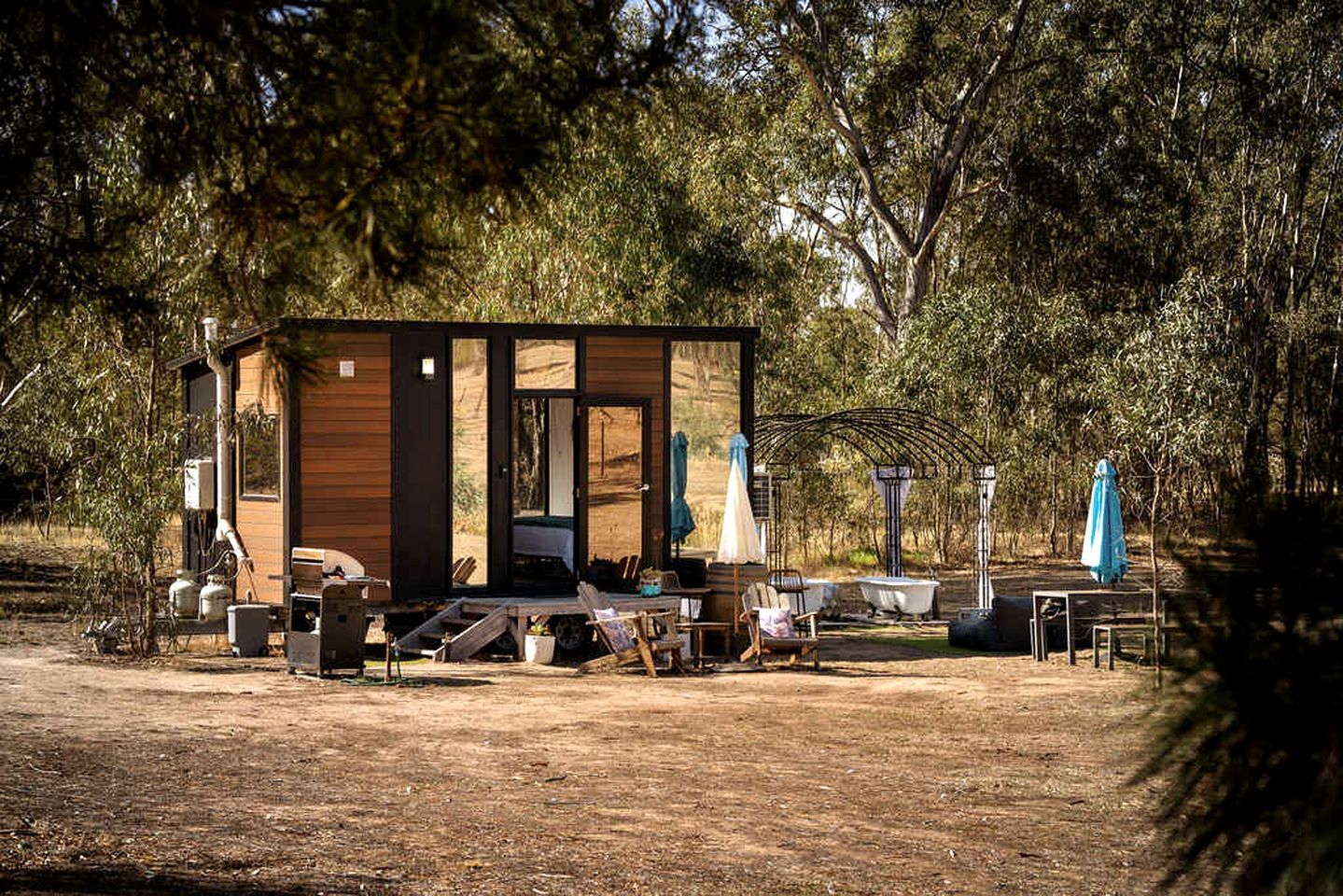A rustic cabin with a wooden exterior, a porch with outdoor seating, and a small pool area.