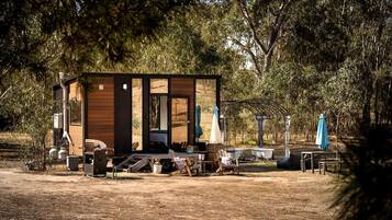 A rustic cabin with a wooden exterior, a porch with outdoor seating, and a small pool area.