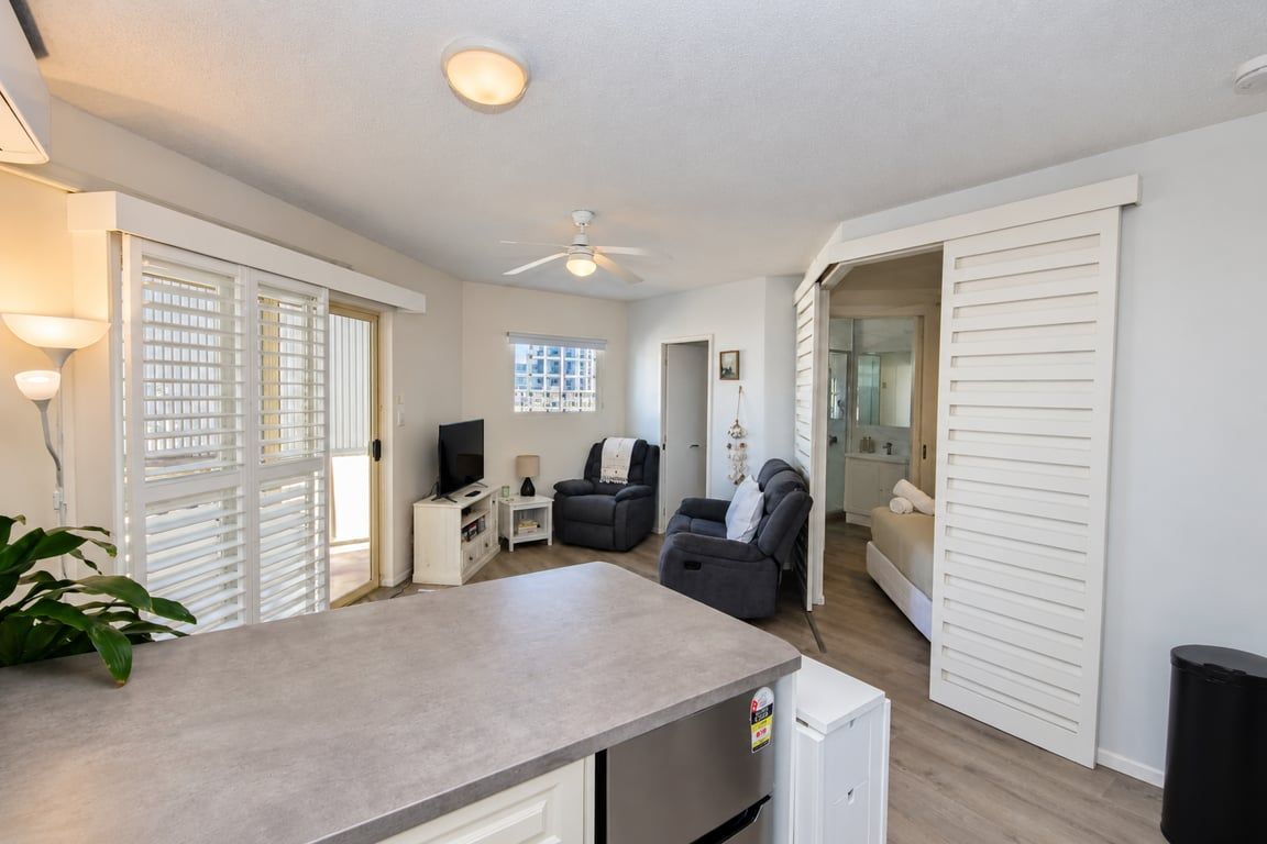 A modern kitchen with a countertop, a refrigerator, and a dining area with a table and chairs.