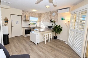A compact kitchen with a microwave, stove, and bar stools.