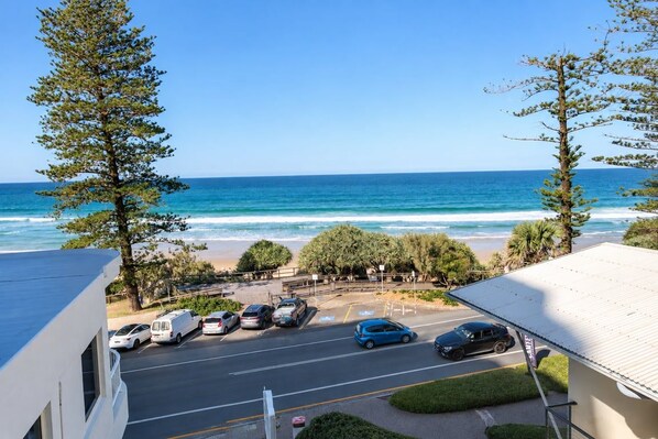 A beachfront property with a parking area, a road leading to the beach, and a view of the ocean.