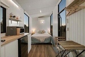 Une chambre à coucher de taille modeste, comprenant un lit, une table de chevet et une fenêtre donnant sur l’extérieur.